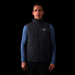 a fit photo of a person wearing the mens ascent stretch vest with 60g primaloft gold insulation in colorway DEEP SPACE with a mens pursuit longsleeve in MINDFUL BLUE underneath