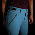 A fit photo of the HIMALI Women's Guide Flex Pant showing the zippered pocket