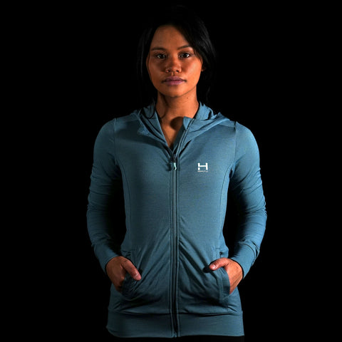 The front view of a model wearing the Women's Momentum YKK Zipper Hoodie with her hands in her front pockets
